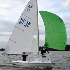 Flying Scot race sails. Fluorescent green spinnaker. Crew rolling the jib under sail.